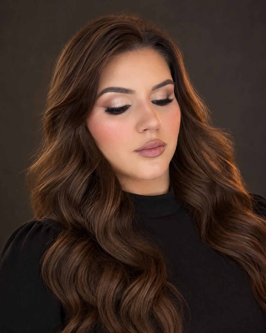 Karina of Studio Karina in soft glam makeup with shimmering eyes, a soft nude lip and long brown waves
